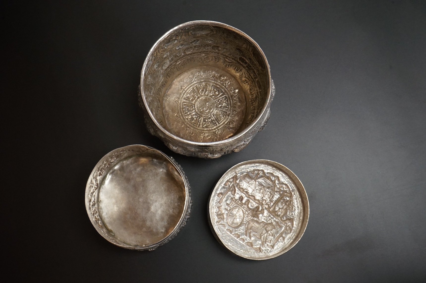 A Burmese embossed white metal circular bowl, signature to the base, diameter 11.4cm, together with a similar circular box and cover, 17oz.